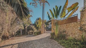 A cobblestone pathway leading to a stone building with tropical vegetation on both sides. - Villa Catalina - Pool - OceanViews - 5 King Suites (San Francisco)