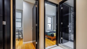 A hallway with a bed, a chair, and a window in the adjacent room. - Spacious 4-bedroom apartment in tranquil New York with AC (New York)