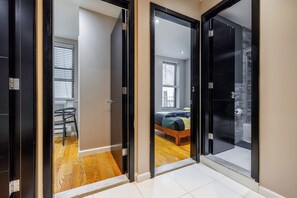 A hallway with a bed, a chair, and a window in the adjacent room. - Spacious 4-bedroom apartment in tranquil New York with AC (New York)