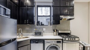 A compact kitchen with a dishwasher, washing machine, stove, and a window above the sink. - Spacious 4-bedroom apartment in tranquil New York with AC (New York)