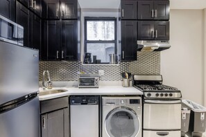 A compact kitchen with a dishwasher, washing machine, stove, and a window above the sink. - Spacious 4-bedroom apartment in tranquil New York with AC (New York)