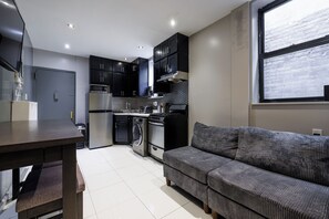 Una cocina compacta con electrodomésticos modernos, un comedor y un sofá.