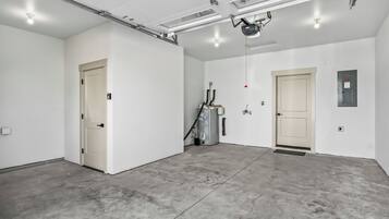 A spacious, well-lit industrial-style room with concrete flooring, two doors, and visible ceiling-mounted equipment.