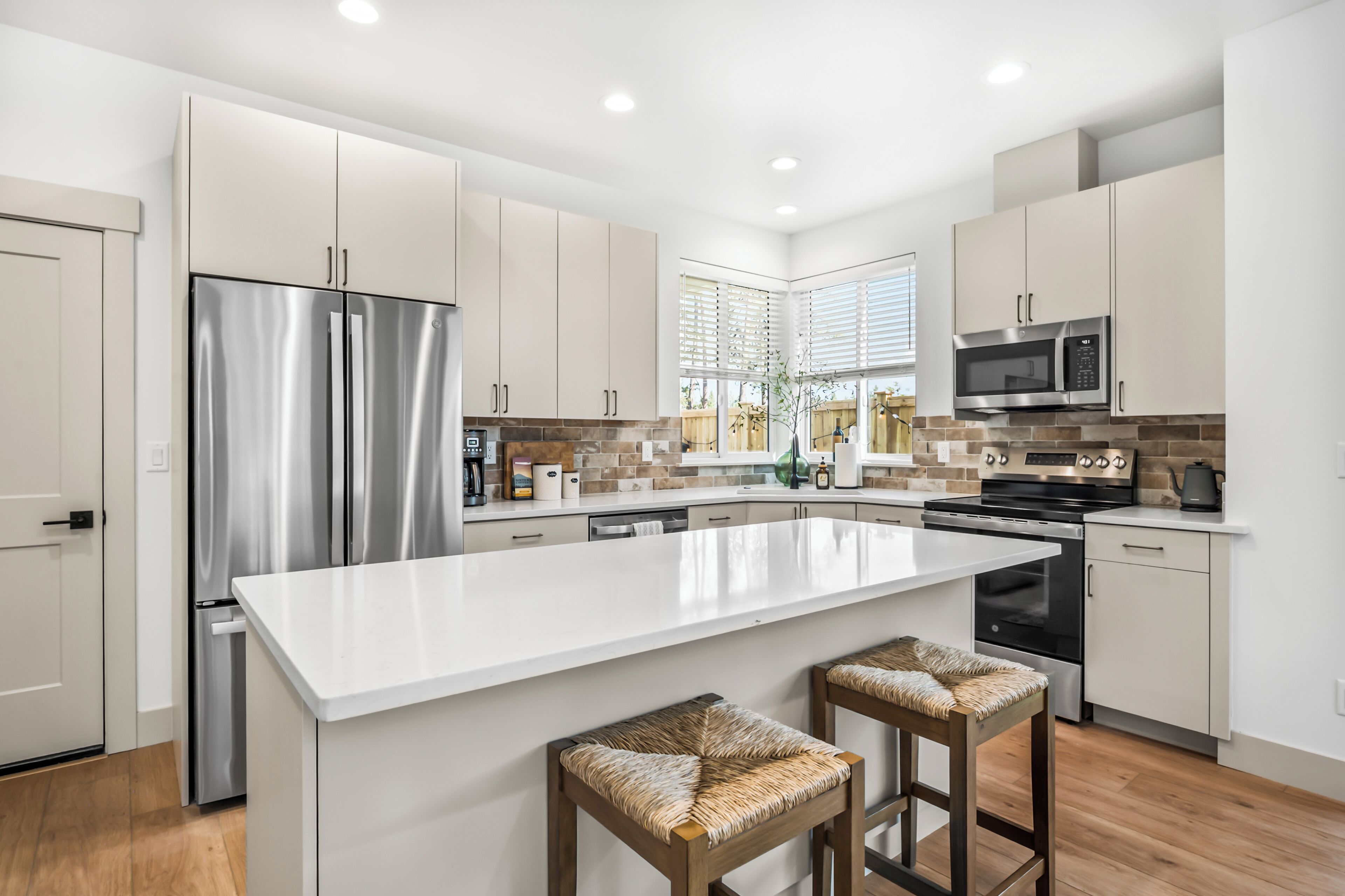 A modern kitchen with stainless steel appliances, a large island, and a view of the outdoors.