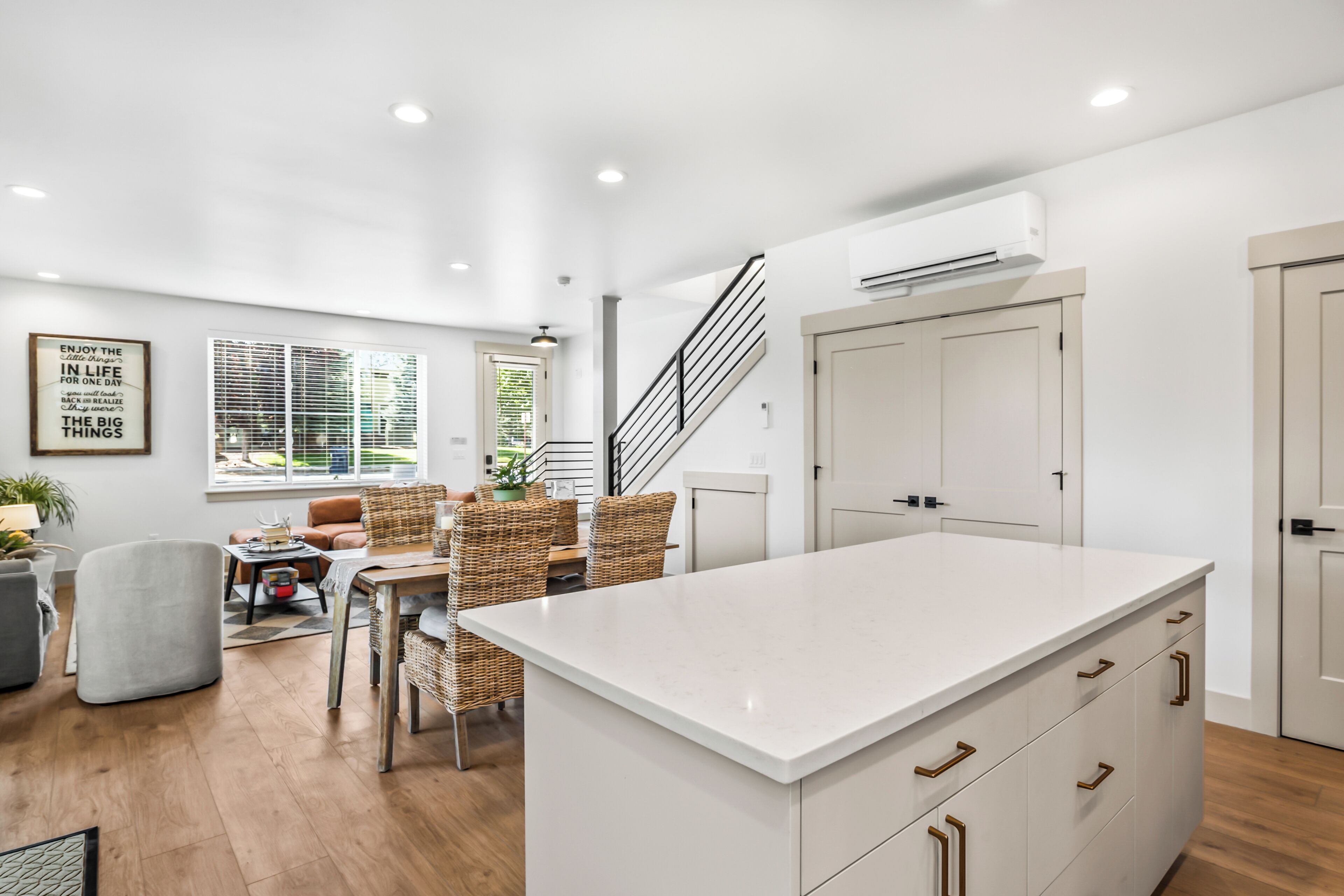 A modern kitchen with a central island, white cabinetry, and a staircase leading to an upper level.