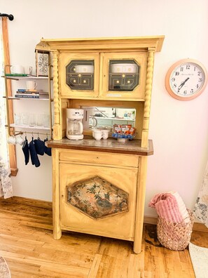 A vintage-style kitchen with a coffee maker, a clock, and a shelf with books and glasses. - Downtown Blush Bungalow and Hot Tub (Boerne)