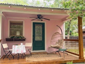 Eine Veranda mit Tisch, zwei Stühlen, einer Hängematte, einem Deckenventilator und einer Fußmatte.