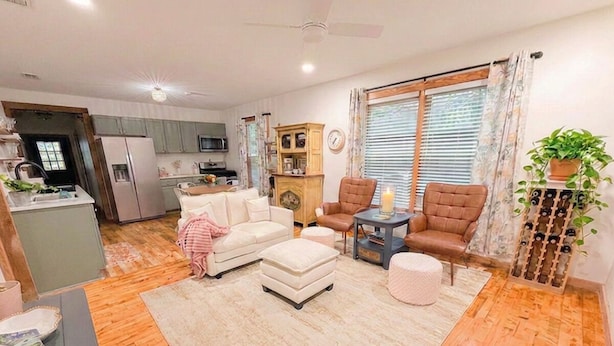 Un salon comprenant un canapé, un pouf et des fauteuils, une petite table avec une bougie et un meuble à bouteilles.