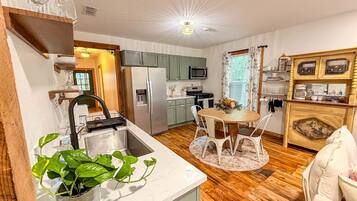 Une cuisine compacte avec un coin repas, un plancher en bois et un îlot central doté de chaises.