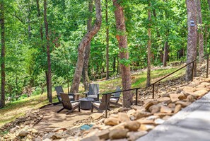 Un espace extérieur aménagé avec une table et des chaises, entouré d’arbres et bordé d’un chemin en pierre.
