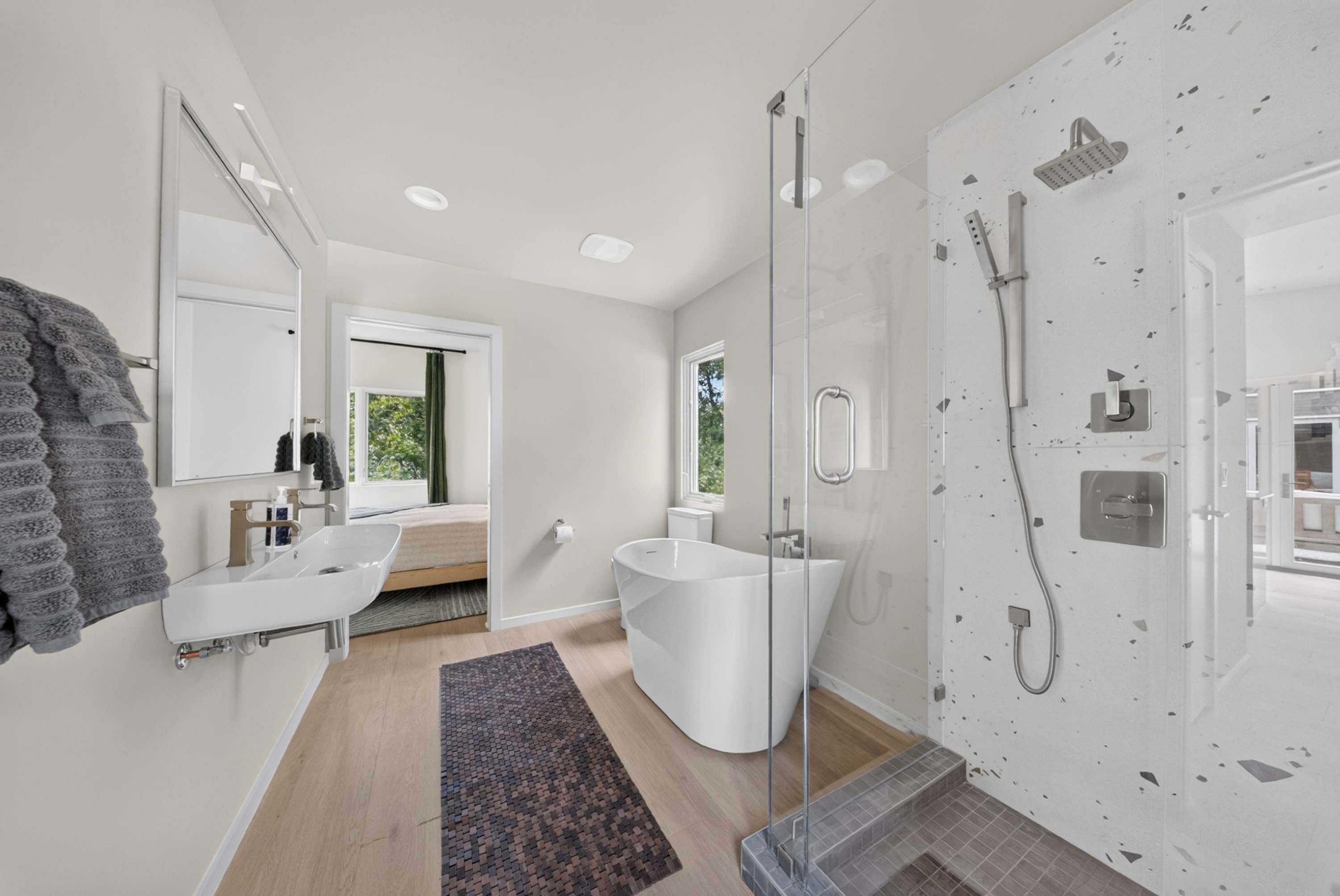 A modern bathroom with a glass-enclosed shower, a white sink, and a large mirror.