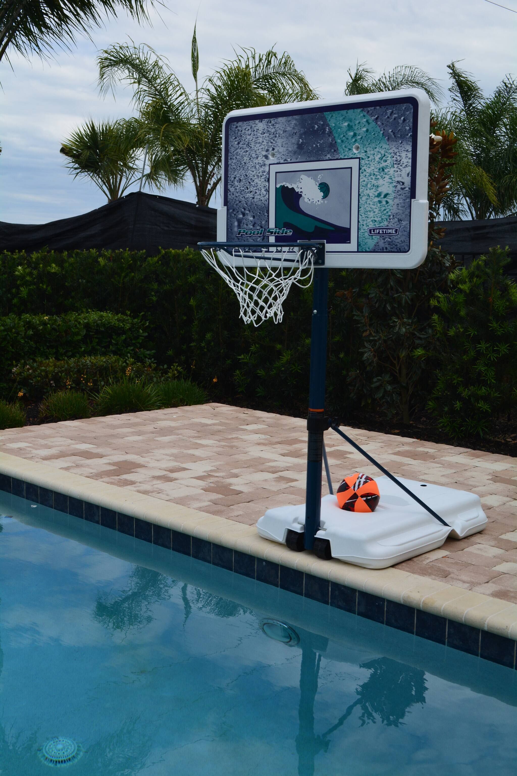 Ein Basketballfeld am Pool mit Netz, einem Rettungsring und dem Schwimmbecken.