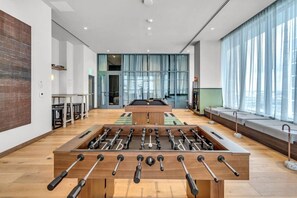 Ein geräumiger Raum mit Tischfußball, Billardtisch und großen Fenstern für viel Tageslicht.