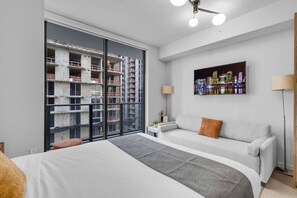 Ein modernes Hotelzimmer mit einem großen Bett, einer Sitzecke, Blick auf die Stadt und einem Balkon mit Baustellenansicht.