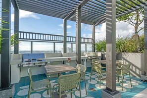 An outdoor patio with a grill, seating, and a view of the city. - Stylish Studio Downtown Pool Gym Sauna (Miami)