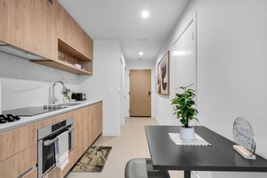 A modern kitchen with wooden cabinets, a black countertop, and a dining table with a potted plant. - Stylish Studio Downtown Pool Gym Sauna (Miami)