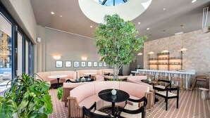 Uma área de estar moderna com assentos, uma árvore central e um bar com prateleiras.