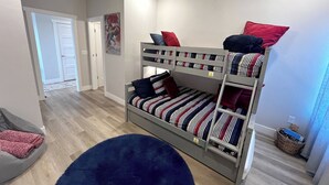 Ein Stockbett mit gestreifter Bettwäsche, ein Deckenventilator und eine Tür zu einem anderen Raum.