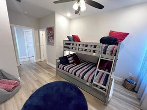 A bunk bed with striped bedding, a ceiling fan, and a door leading to another room. - Blue Horizon-Panoramic Lake View on Indian Point (Branson)