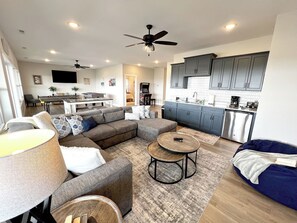 A modern living room with a sectional sofa, a coffee table, and a dining area with a kitchen in the background. - Blue Horizon-Panoramic Lake View on Indian Point (Branson)