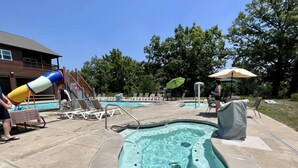Ein Poolbereich mit Whirlpool, Liegestühlen und einer Rutsche.