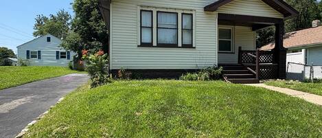 A single-story house with a front porch, a stone retaining wall, and a clear sky.
