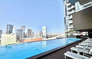 A rooftop pool with a city skyline view, lounge chairs, and a modern building structure. - Apartment Andares - Wonderful 3-bedroom apartment with AC in charming Zapopan (Zapopan)