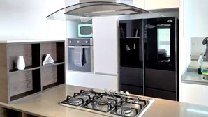 Et moderne køkken med en central ø, rustfrie stål hvidevarer og et stilrent design.