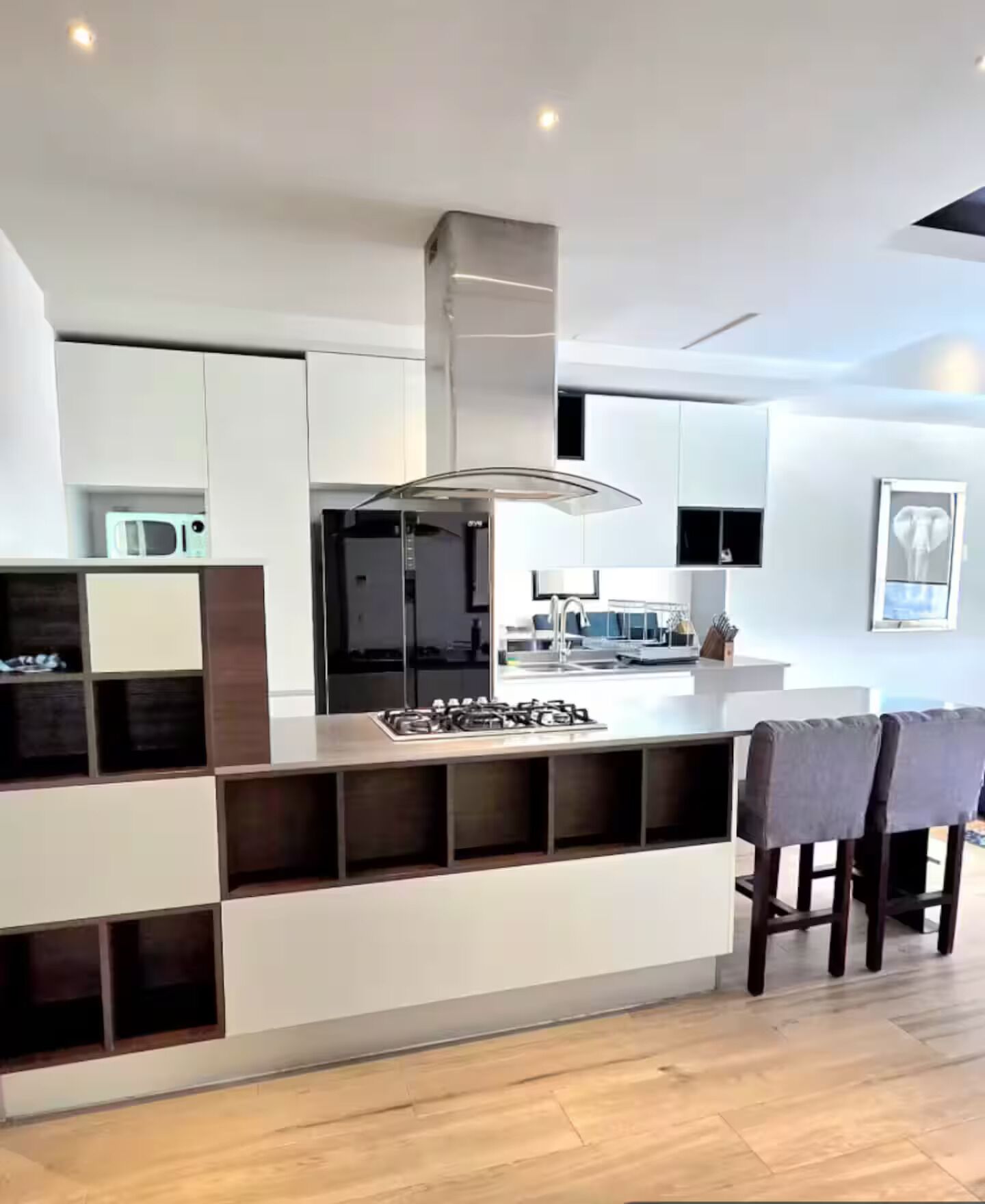 Una cocina moderna con una isla central, electrodomésticos integrados y un área de comedor con sillas.