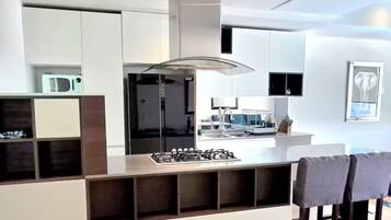 Una cocina moderna con una isla central, electrodomésticos integrados y un área de comedor con sillas.