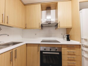 A kitchen with wooden cabinets, a stainless steel range hood, a built-in oven, and a coffee maker. - Bravissimo Pons i Martí Baix, 1-bedroom apartment (Girona)