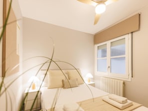 Een slaapkamer met een bed, nachtlampjes, een raam en een radiator.