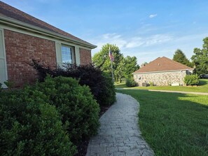 A residential property with a paved pathway leading to a brick house, a stone house in the background, and a flagpole with an American flag. - Spacious Home Near Lake, Free Boat Parking (Somerset)