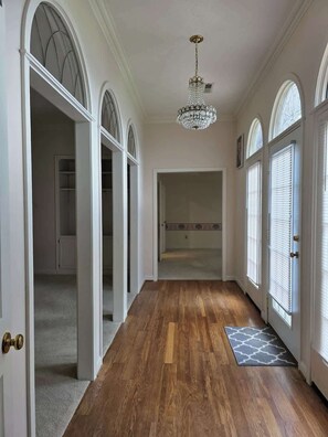 A hallway with wooden flooring, white walls, and arched doorways leading to rooms. - Spacious Home Near Lake, Free Boat Parking (Somerset)