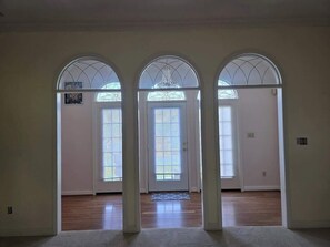 Un pasillo con tres arcos que dan a habitaciones, cada una con ventana y puerta.