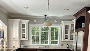 A kitchen with a central island, dark wooden cabinets, a stainless steel refrigerator, and a large window providing natural light. - Beautiful home in desirable Riverlocks neighborhood, walkable to Kennebunkport (Kennebunk)