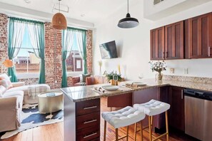 Une cuisine moderne dotée d’un îlot central, de meubles en bois et d’un coin repas comprenant un canapé et des tabourets de bar.