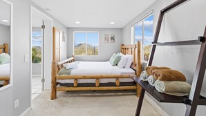 A bedroom with a wooden bed, a view of the outdoors, and a shelf with blankets. - Natures Escape - Game Room, Spa, Sauna, OMG Views! (Escondido)