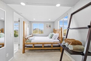 A bedroom with a wooden bed, a view of the outdoors, and a shelf with blankets. - Natures Escape - Game Room, Spa, Sauna, OMG Views! (Escondido)