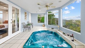 A modern room with a hot tub, a ceiling fan, large windows, and a view of the outdoors. - Natures Escape - Game Room, Spa, Sauna, OMG Views! (Escondido)