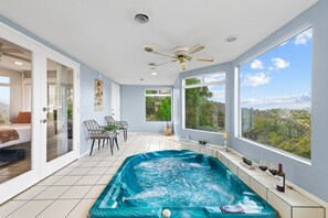 A modern room with a hot tub, a ceiling fan, large windows, and a view of the outdoors. - Natures Escape - Game Room, Spa, Sauna, OMG Views! (Escondido)