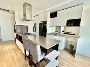 Ett modernt kök med en central köksö, vitvaror i rostfritt stål och en stilren, minimalistisk design.