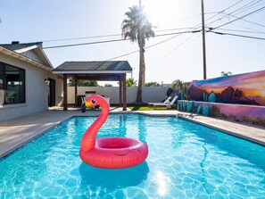 A swimming pool with a flamingo float, a patio area, and a mural on the wall. - Casa Sol - Desert Retreat w/ Pool & Large Patio 4 Bed/3bath (Scottsdale)