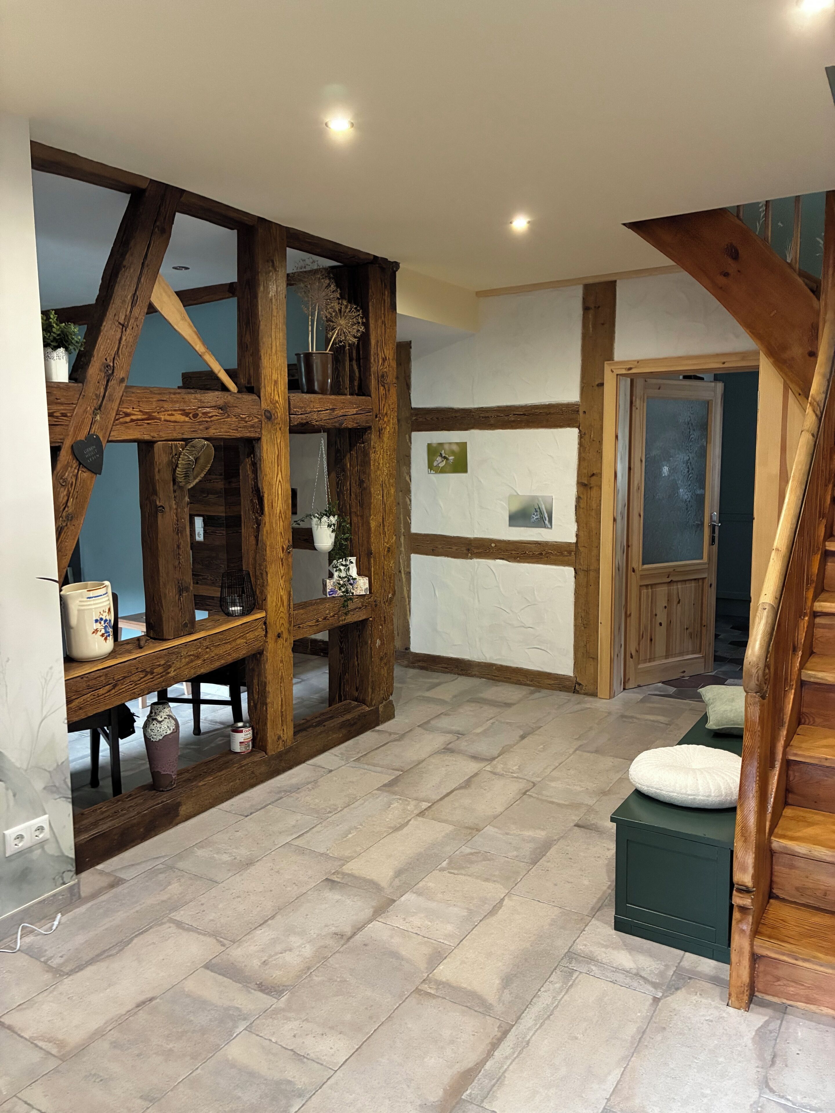 A hallway with exposed wooden beams, a staircase, and a door leading to another room.