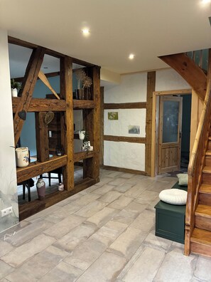 A hallway with exposed wooden beams, a staircase, and a door leading to another room. - Renovated farmhouse perfect for nature lovers and photo enthusiasts (Reurieth)