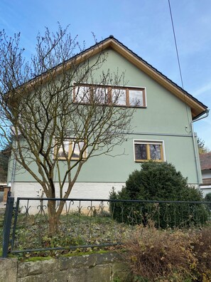 A two-story house with a green facade, a visible window, and a tree in the front yard. - Renovated farmhouse perfect for nature lovers and photo enthusiasts (Reurieth)