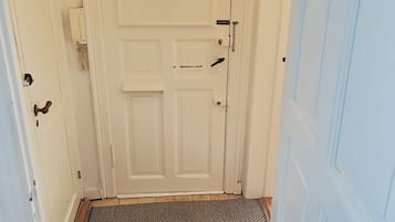 A hallway with a white door, a doormat, and a pair of shoes on the floor.