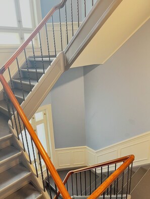 A spiral staircase with wooden handrails and metal balusters, leading to a landing with a white door. - Beautiful, spacious apartment in Copenhagen (København)