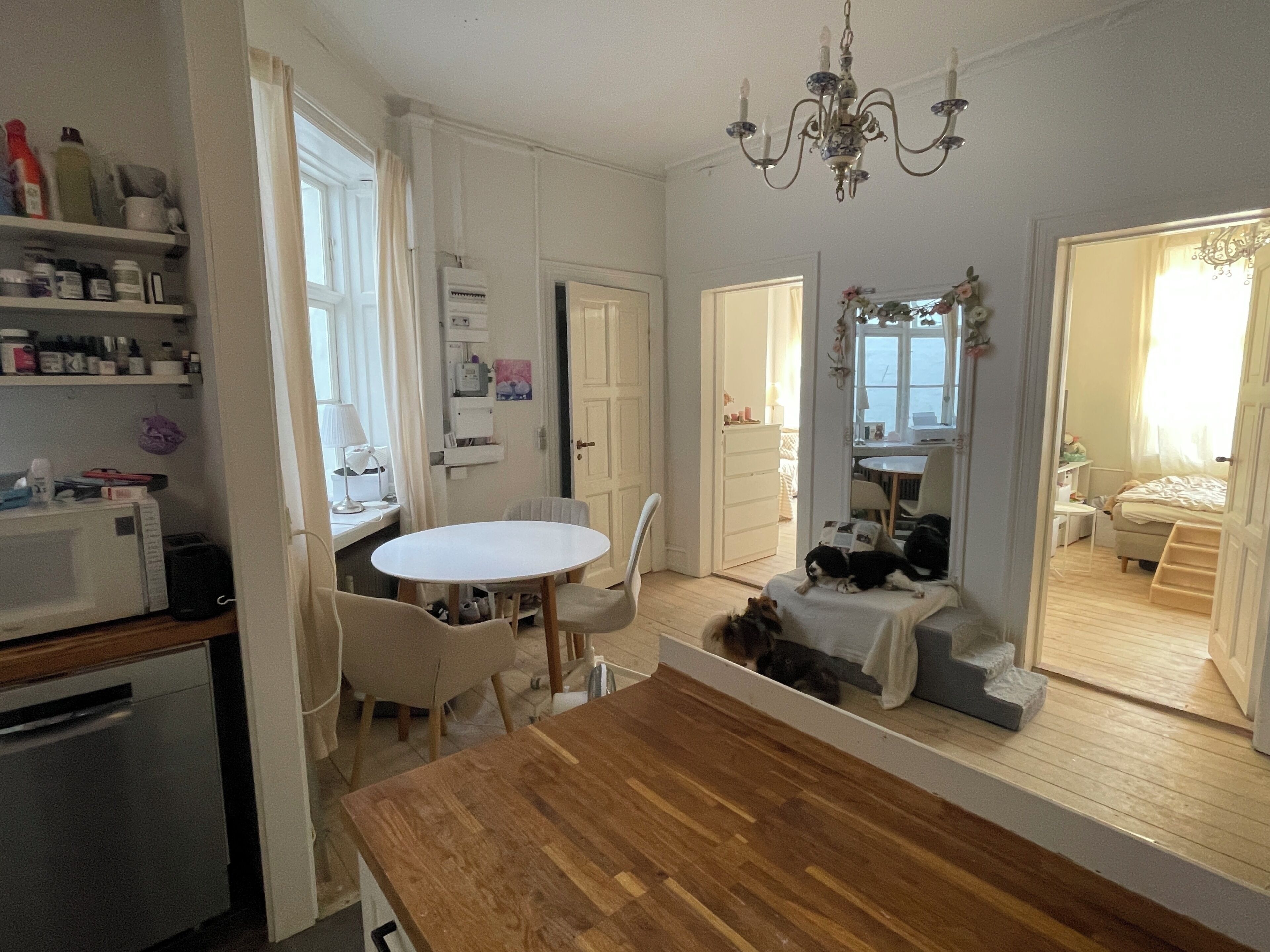 A modern kitchen with white cabinets, a wooden countertop, and a dining area with a white table and chairs.