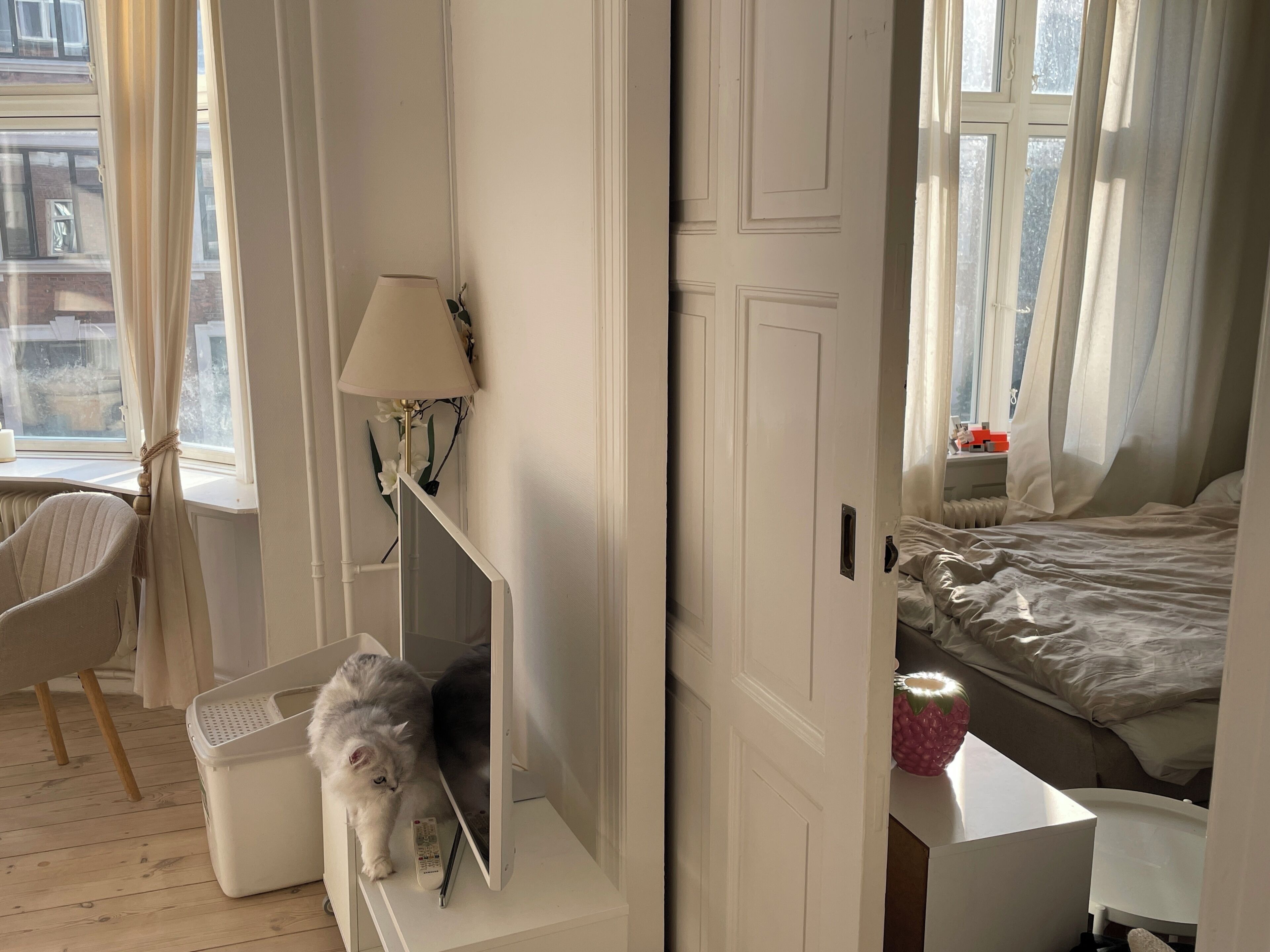 A room with a bed, a chair, a lamp, and a window with curtains.